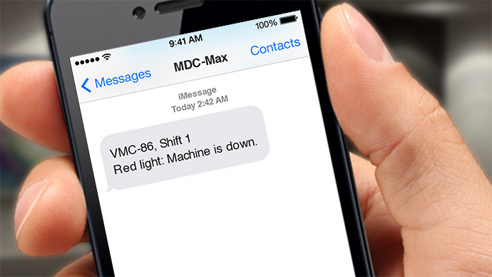 A hand holding a smartphone with a text message that read "VMC-86, Shift 1 Red light: machine is down" from "MDC-Max".