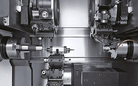 Looking inside a DMG Mori Seki CNC lathe machine with different metal tools and turrets.