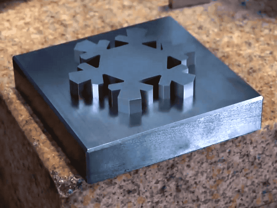A GIF of a metal snowflake shape sinking into a metal block.