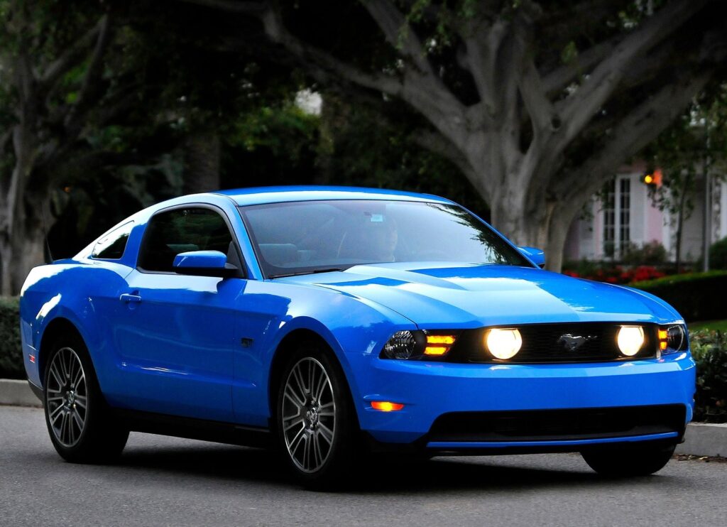 An image of a blue sports car (Mustang GT) on a neighborhood street.